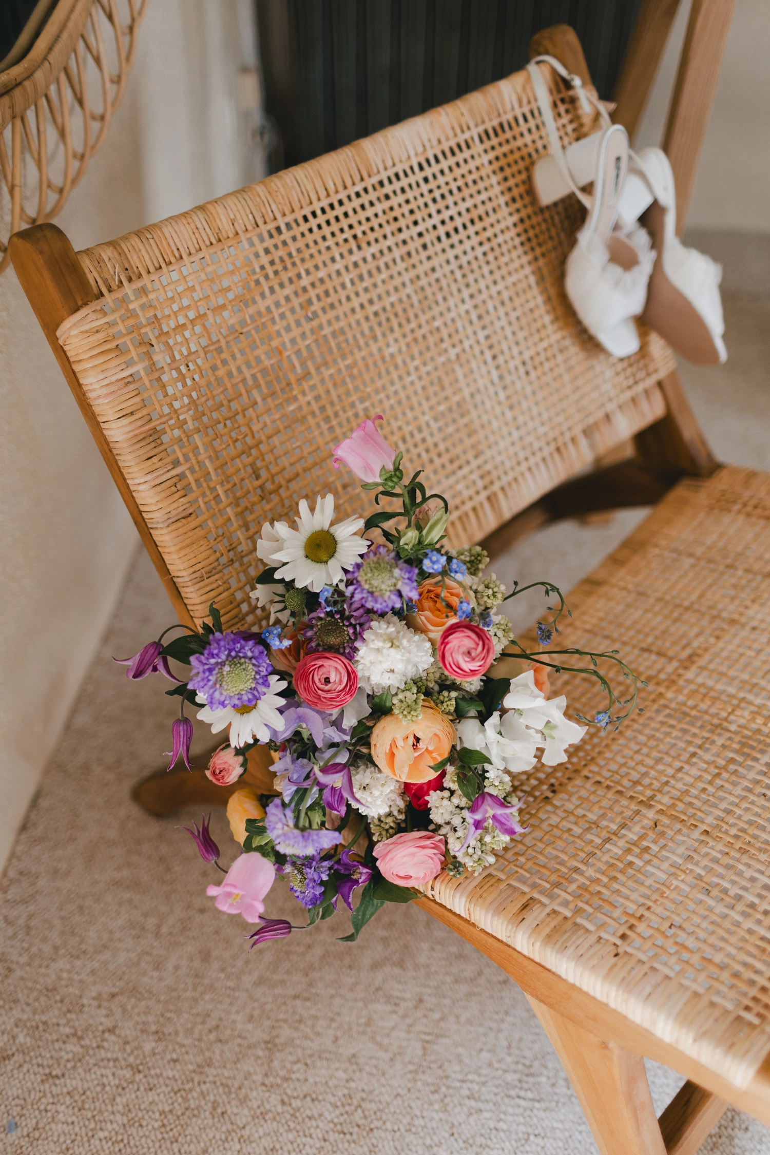 Un bouquet est posé sur une chaise dans la chambre de la marié, et également la paire de chaussure son contre la chaise.