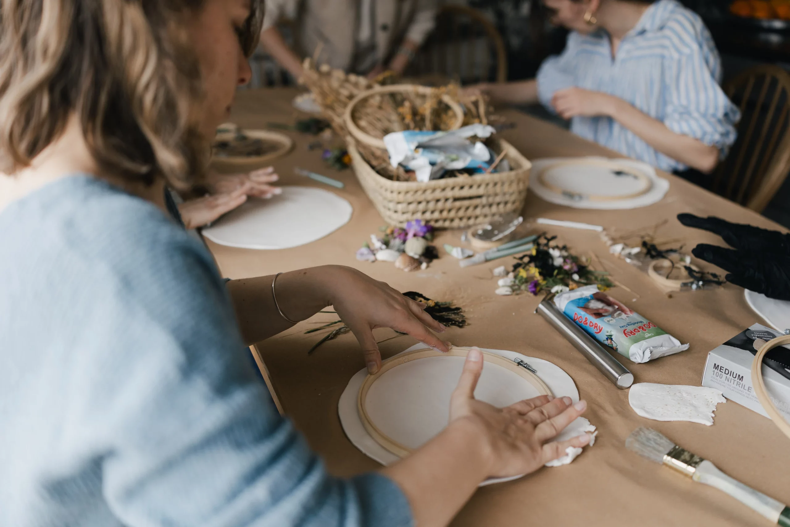 Une femme se tient assise devant une table et avec ses mains elle empreinte un cercle sur une pâte.