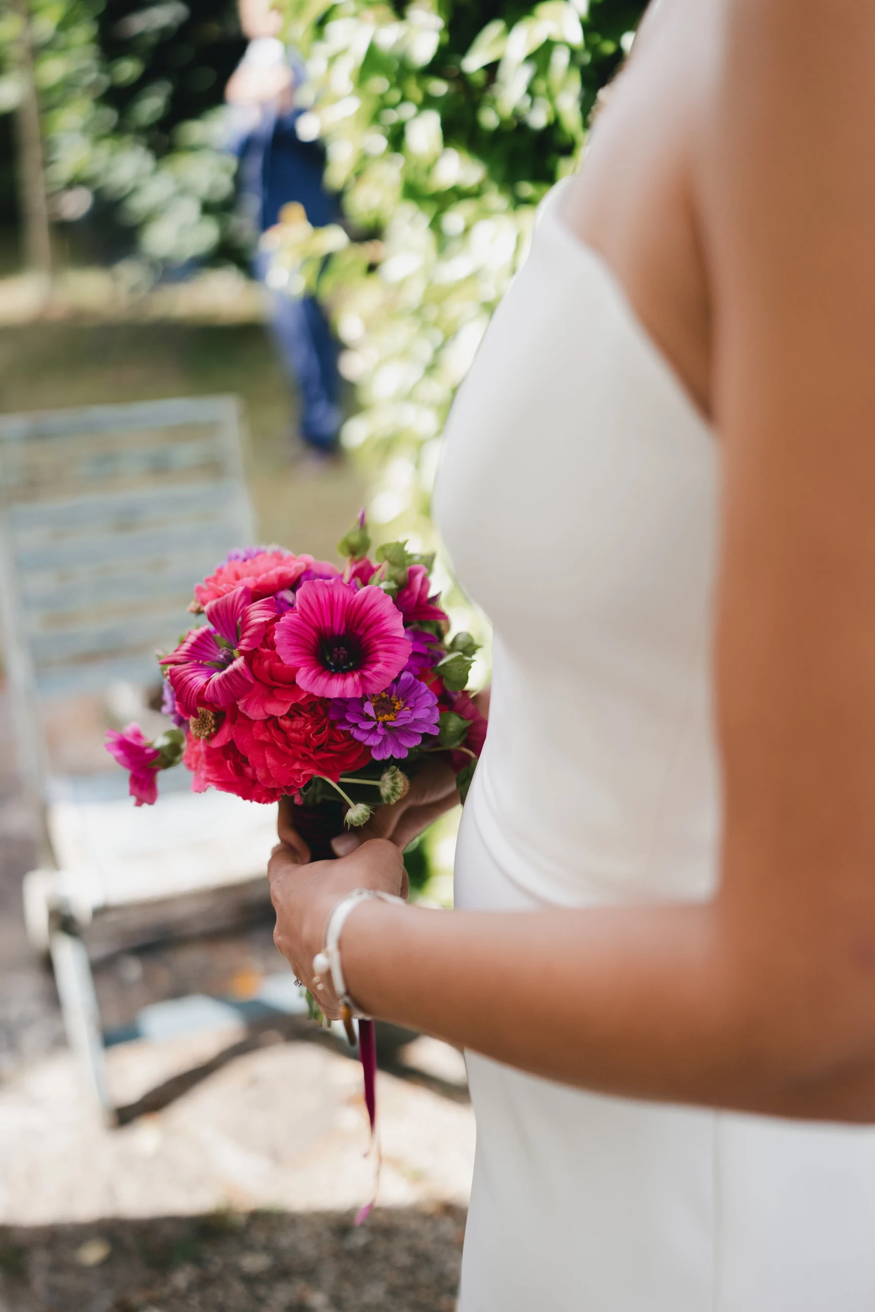 Bouquet de fleurs, qui est tenant entre les mains d'une femme vêtue d'une robe blanche.