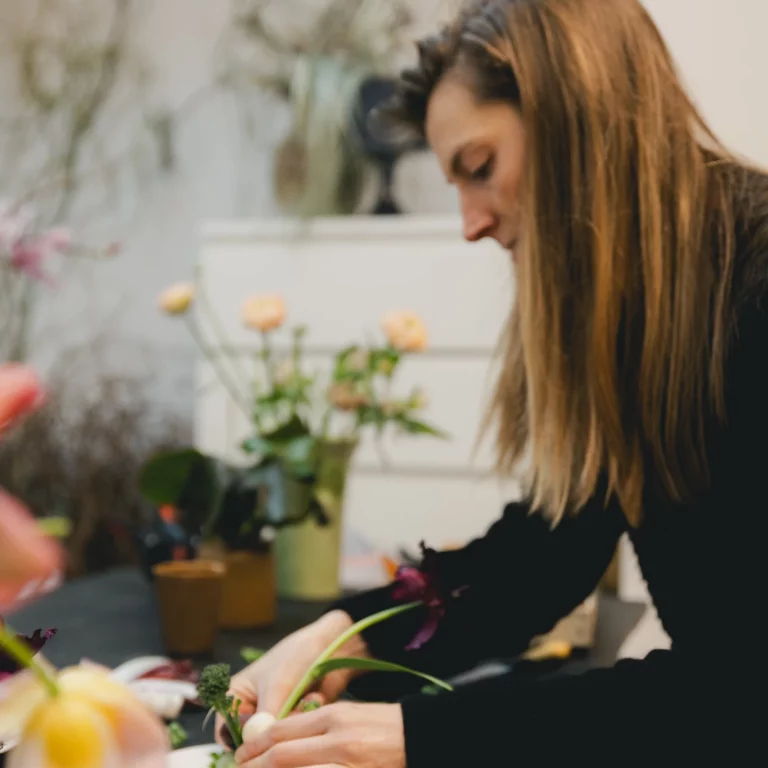 Portrait d'une designer florale entrain de réaliser une composition dans son atelier à Lille.