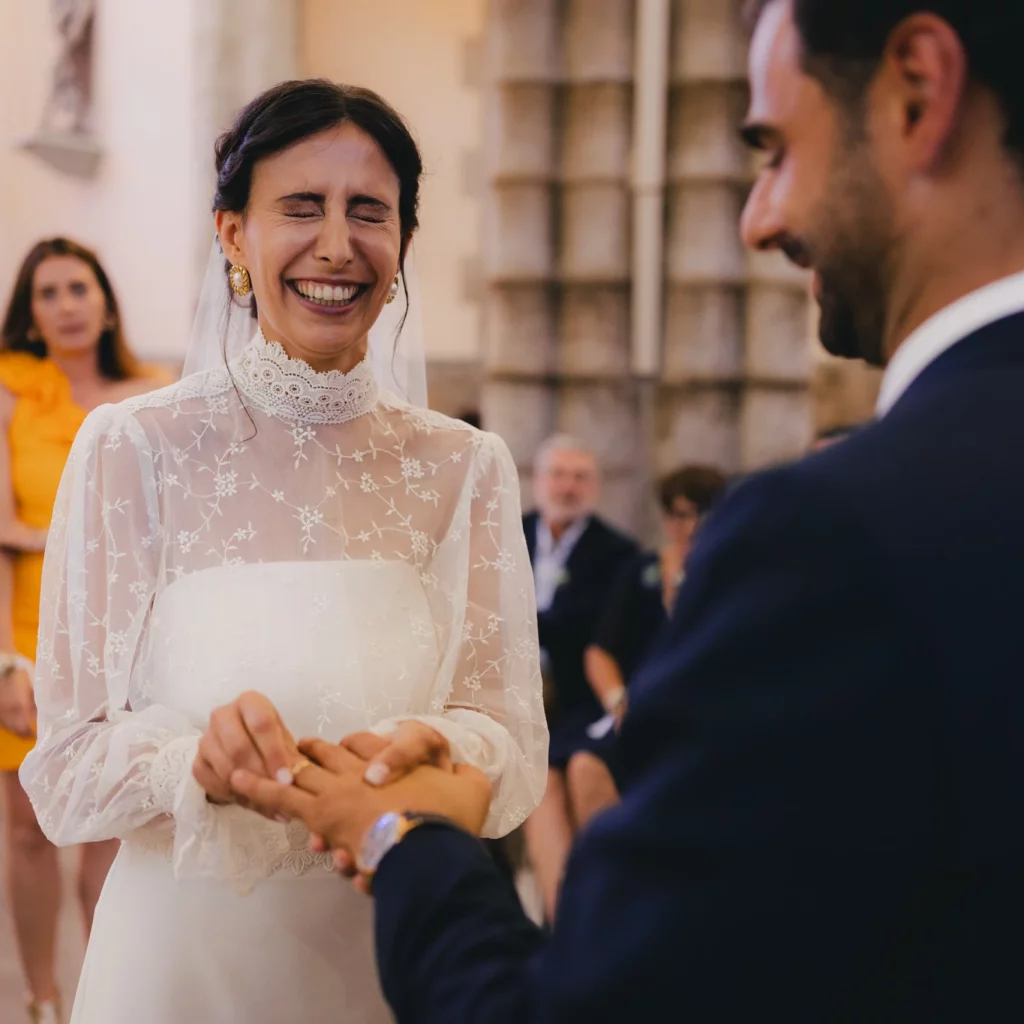 Une femme en robe blanche, passe une alliance autour du doigt de son époux.