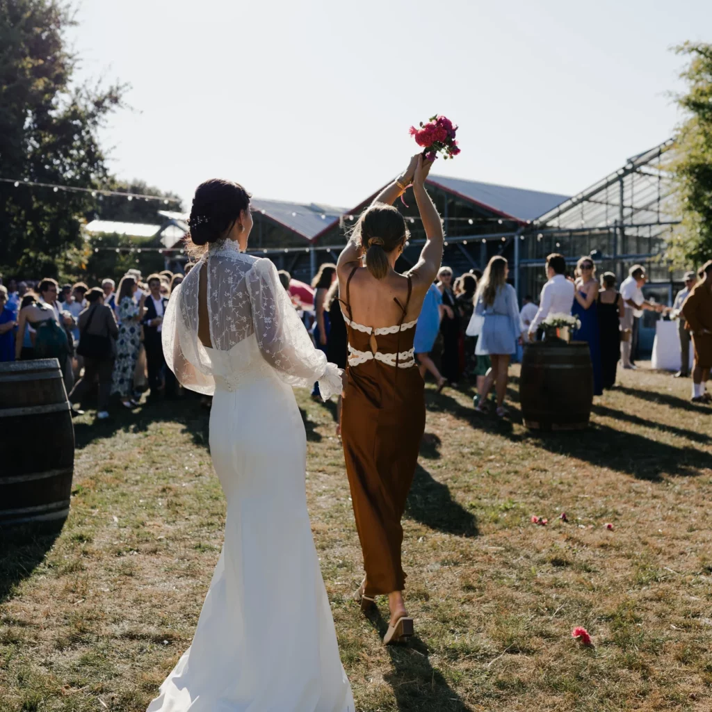 Une mariée est début et face à elle une invitée ayant attrapé le bouquet de fleurs.
