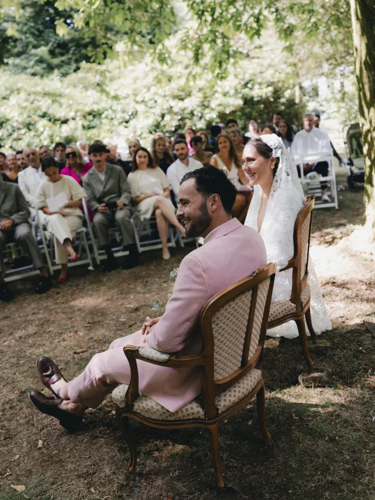 domethilde_photographe_mariage_bretagne_ceremonie Une cérémonie en extérieur, où deux mariés sont assis l'un à coté de l'autre regardant dans la même direction.